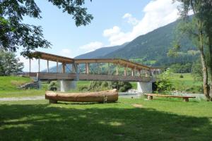 a wooden bridge over a river with a large canoe in the grass at Haus Sagmeister in Steinfeld