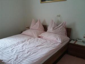 a bed with white sheets and pillows on it at Haus Sagmeister in Steinfeld +6 photos