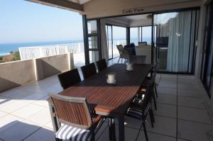 a wooden table and chairs on a balcony with the ocean at CodsView Beach House in Pennington