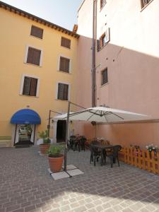 un patio con tavoli e ombrelloni di fronte a un edificio di Il Cavallino a Fossombrone