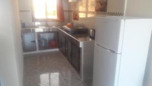 La cuisine est équipée d'un réfrigérateur blanc et de placards en bois. dans l'établissement Appartements Playa, à Saïdia