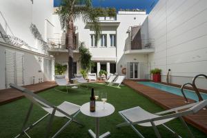 a patio with chairs and a table with a bottle of wine at La Alcoba del Agua Hotel Boutique in Sanlúcar de Barrameda