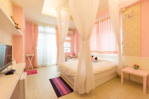 een slaapkamer met een hemelbed en gordijnen bij Tainan Minuet in Tainan