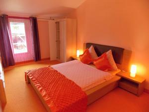 a bedroom with a bed with orange pillows and a window at Le Petit Breuil in Verteillac