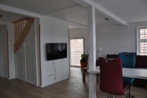 a living room with a table and a tv on a wall at Hafenblick vom Kapitänshaus in Flensburg