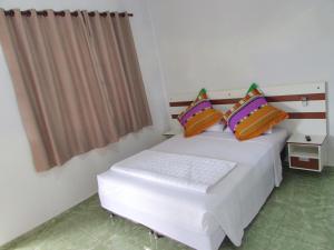 a bedroom with two beds and a window at Pousada Tia Ilda in Pirenópolis