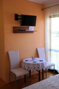 a dining room table with two chairs and a tv on the wall at Apartments Milatic in Jelsa