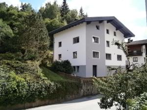 una casa blanca en una colina con árboles en Ferienwohnung Nuener, en Grins