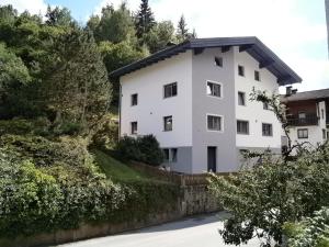 a white house on a hill with trees at Ferienwohnung Nuener in Grins