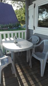 - une table et des chaises blanches sur une terrasse couverte dans l'établissement Sobie-Wyspa domki, à Gdańsk