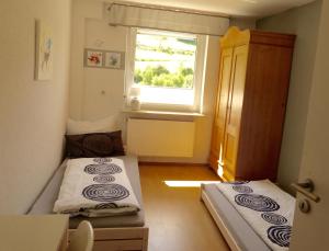2 Betten in einem kleinen Zimmer mit Fenster in der Unterkunft Ferienwohnung rundumgruen in Olpe