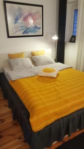 Una cama con una manta amarilla encima. en Loft Rooms - centrum - bezpłatny parking, en Ełk