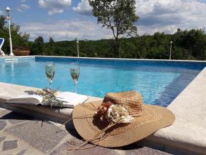 een hoed en een boek op een tafel naast een zwembad bij Vila Vesna in Grožnjan