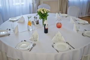 a white table with white plates and flowers on it at Agropark - Dworek pod Lipą in Sobków
