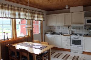 a kitchen with white cabinets and a wooden table at Backs Semesterby in Duved