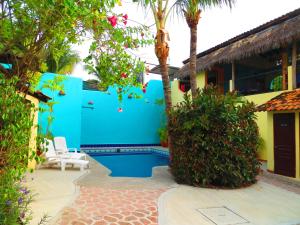a house with a blue wall and palm trees at La Cruz Inn in Cruz de Huanacaxtle