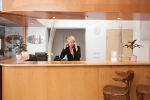 a woman talking on a cell phone behind a counter at Hotel Chotol in Horoměřice