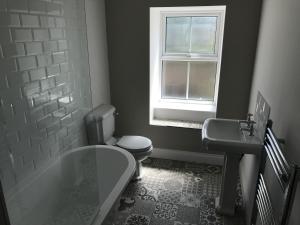 a bathroom with a tub and a toilet and a window at The Manor House in Fenwick +18 photos