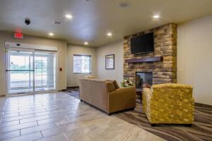 a living room with two chairs and a fireplace at Cobblestone Hotel & Suites - Orrville in Orrville