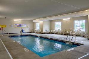 una piscina en una habitación con sillas y mesas en Cobblestone Hotel & Suites - Orrville, en Orrville