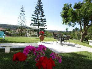 a garden with a table and chairs and flowers at Hotel Louro in Óbidos