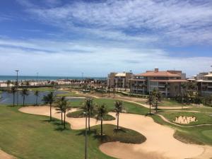 a golf course at a resort with palm trees at Apartamento - Resort Golf Ville in Aquiraz