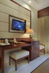 a room with a desk with a television on a wall at Tebesaya Cottage by Pramana Villas in Ubud