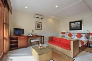 a hotel room with a bed and a red couch at Tebesaya Cottage by Pramana Villas in Ubud