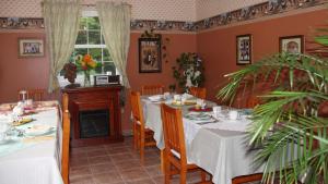 a dining room with white tables and a fireplace at Arkadia Eastman B&B in Eastman