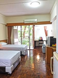 ein Hotelzimmer mit 2 Betten und einem TV in der Unterkunft Rio Monte Residence in Bangkok