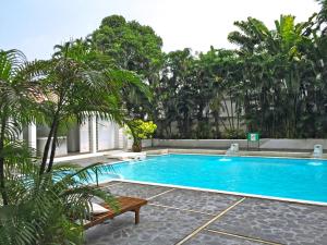 a swimming pool with a bench and palm trees at Rio Monte Residence in Bangkok