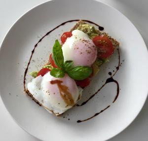 a white plate with a dessert with eggs and tomatoes at Refreshstay in Palmerston North