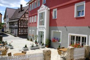 Gasthaus Traube في Dettingen an der Erms: مبنى احمر وبيض مع طاولة وكراسي