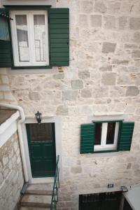 a stone building with green doors and windows at Bed & Breakfast Vila Baguc in Split