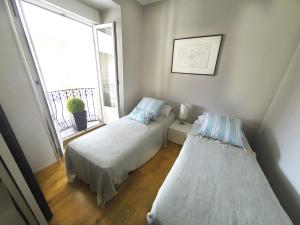 2 camas en una habitación pequeña con ventana en Luxury Arquillos Vitoria, en Vitoria-Gasteiz
