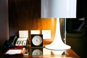 a table with a lamp and a clock and a phone at Jianguo Hotel in Beijing