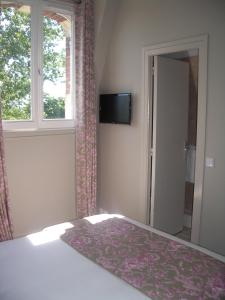 a bedroom with a bed and a window and a television at La Maison d'Emilie in Houlgate +33 photos