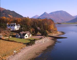 een huis op een heuvel naast een waterlichaam bij Loch Leven Hotel & Distillery in Glencoe