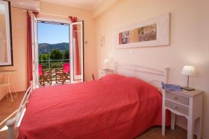 una camera con letto rosso e balcone di Villa REGINA a Kondoyenádha