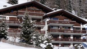 ein großes Apartmenthaus mit einem Weihnachtsbaum im Schnee in der Unterkunft Haus Azalea in Davos