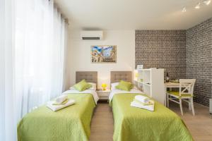 een slaapkamer met 2 bedden met groene lakens en een bureau bij Ink Apartment in Split