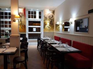 un comedor con mesas, sillas y ventanas en Hôtel Bistrot Le Marceau, en Limoges