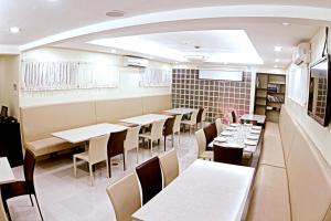 una sala da pranzo con tavoli e sedie bianchi di The Center Suites a Cebu City