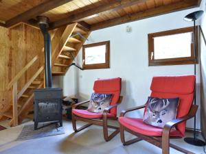 Saint-Quirin的住宿－Cosy chalet with river，一间设有两张红色椅子和燃木火炉的房间