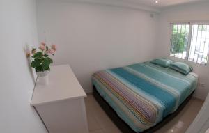 ein Schlafzimmer mit einem Bett und einer Vase aus Blumen auf einem Tisch in der Unterkunft Villa Marysol sleeps 6 in Fuengirola