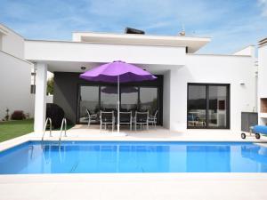 uma villa com uma piscina e um guarda-sol roxo em Modern villa with private swimming pool em Famalicão