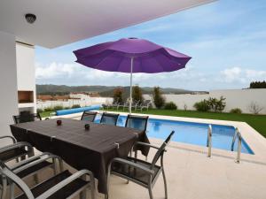 uma mesa com um guarda-sol roxo e cadeiras e uma piscina em Modern villa with private swimming pool em Famalicão