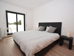 een witte slaapkamer met een groot bed en een raam bij Modern villa with private swimming pool in Famalicão