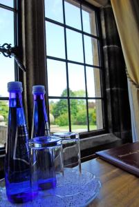 two blue bottles and glasses on a table with a window at Dunsley Hall Country House Hotel in Whitby