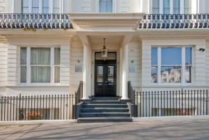 a white house with a black door and stairs at 20 Hertford Street - Mayfair Apartments in London